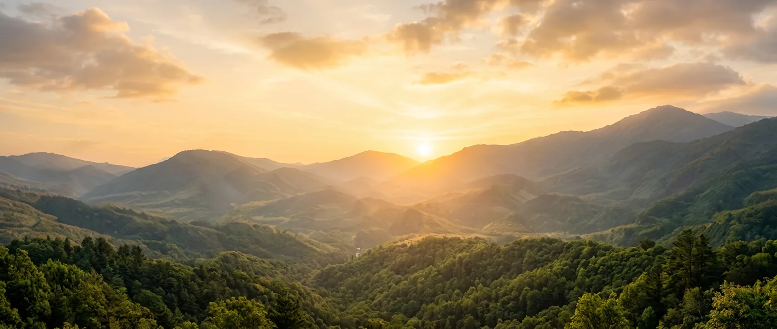 Sunrise light spreading across layered green mountain ridges